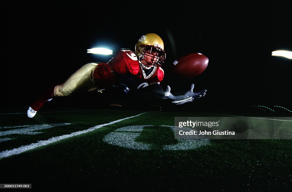 Football player diving to catch ball