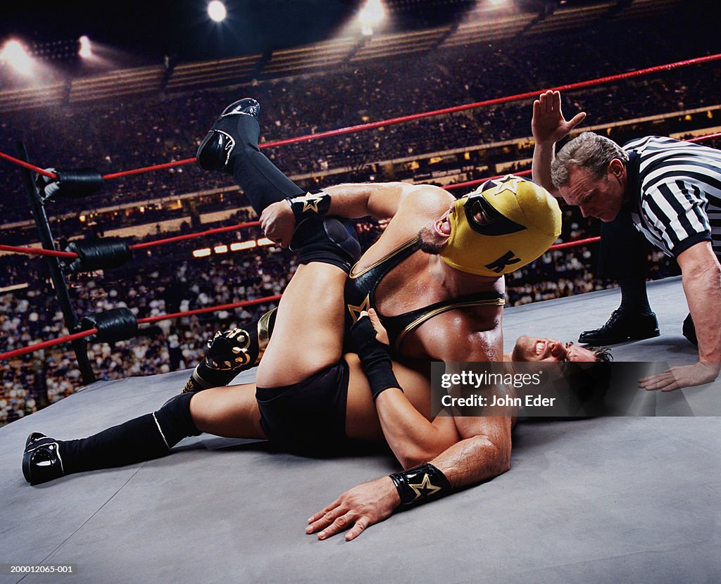 Pro wrestler pinning opponent on mat, referee counting down