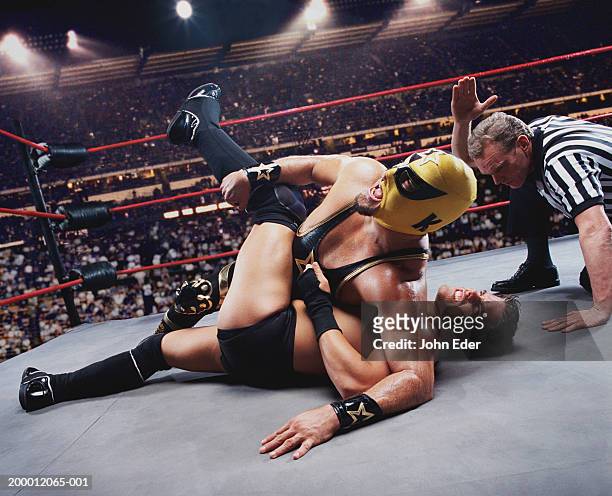 pro wrestler pinning opponent on mat, referee counting down - combat sport stock pictures, royalty-free photos & images