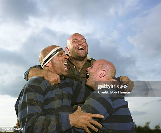 three rugby players embracing and smiling - amateur rugby stock pictures, royalty-free photos & images