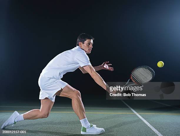 man playing tennis on outdoor court, night - tennis stock-fotos und bilder