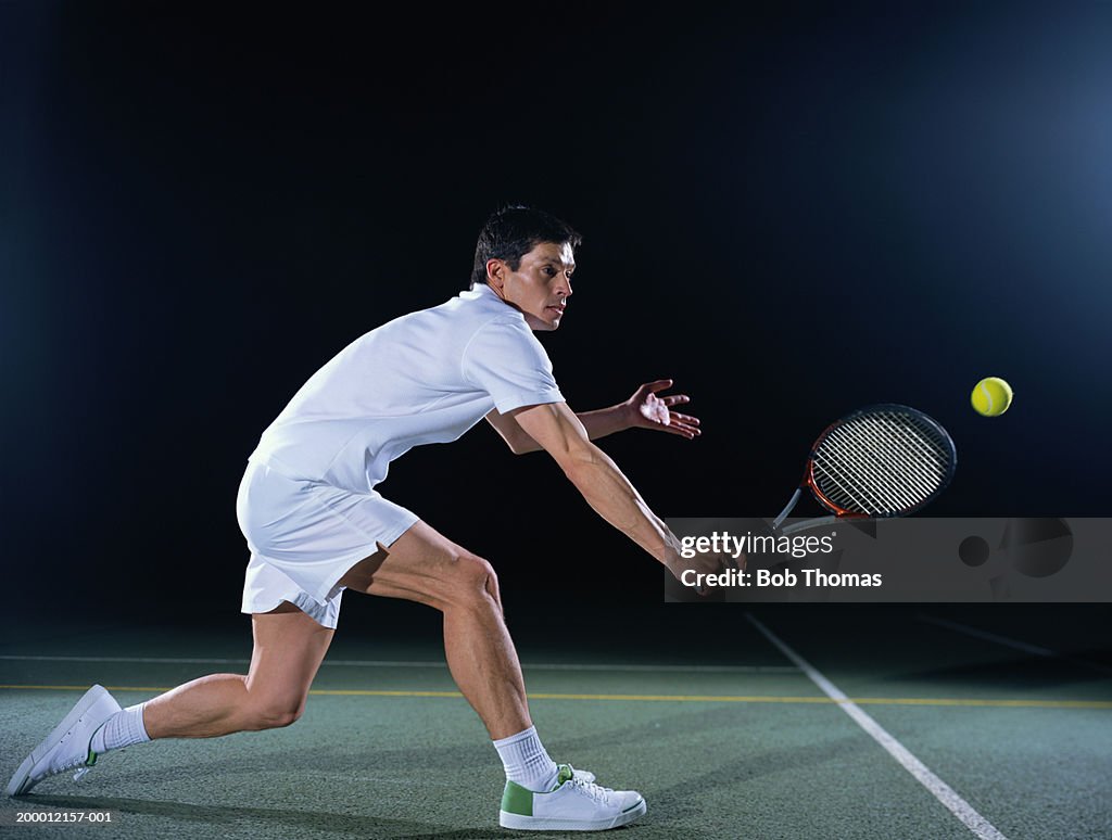 Man playing tennis on outdoor court, night