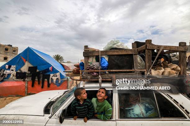 Children sit inside a vehicle loaded with items secured by rope as people flee from Rafah in the southern Gaza Strip on February 13, 2024 north...