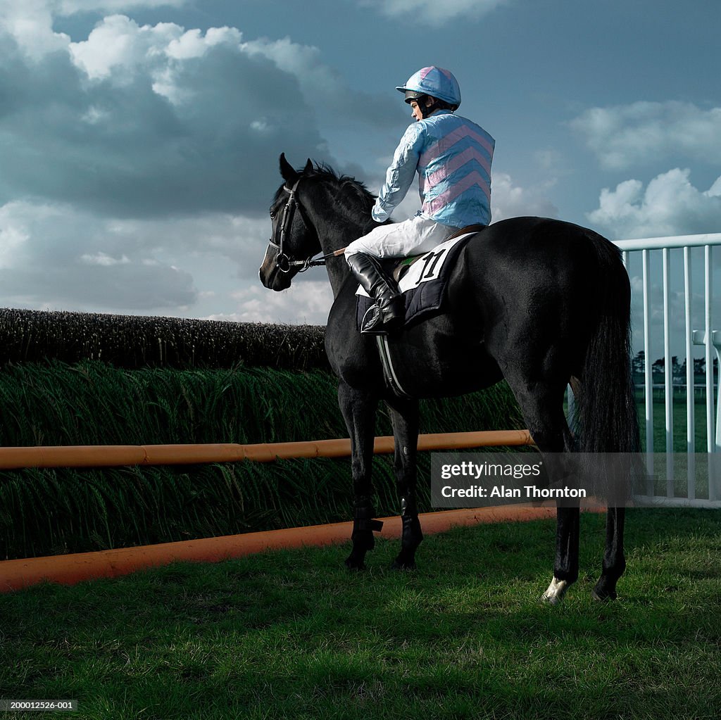 Teenage jockey (15-17) on horse in front of jump