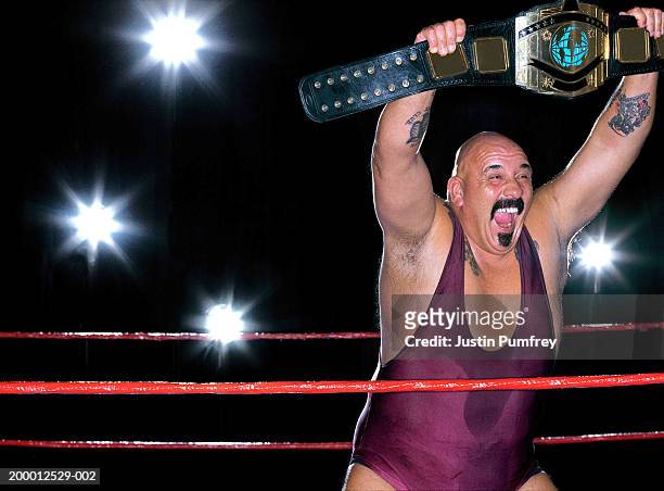 male wrestler holding up championship belt in ring - belt stock pictures, royalty-free photos & images
