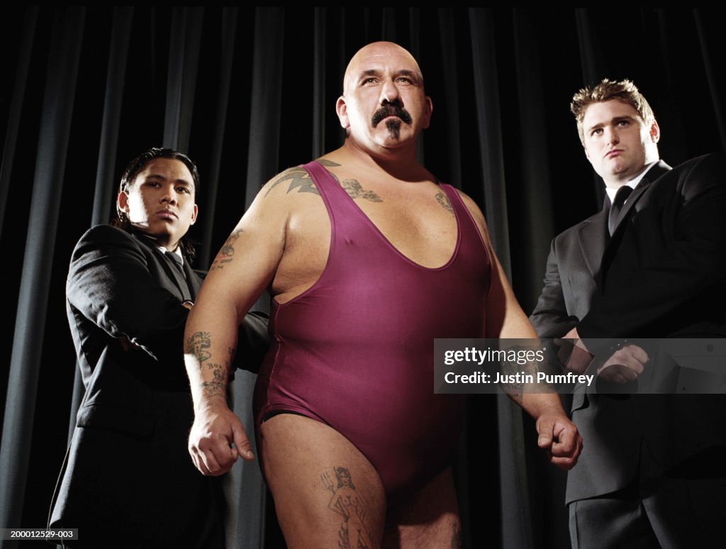 Male wrestler flanked by two bodyguards