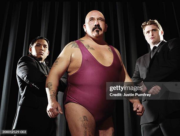 male wrestler flanked by two bodyguards - bodysuit stock pictures, royalty-free photos & images
