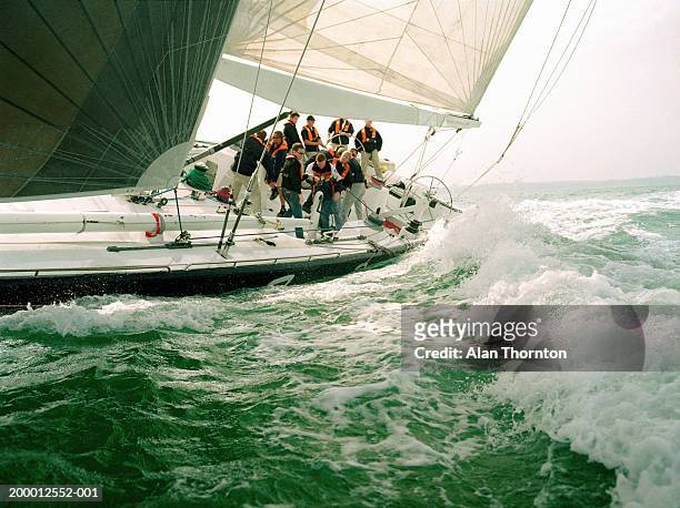 crew sailing yacht through rough sea - segeln stock-fotos und bilder