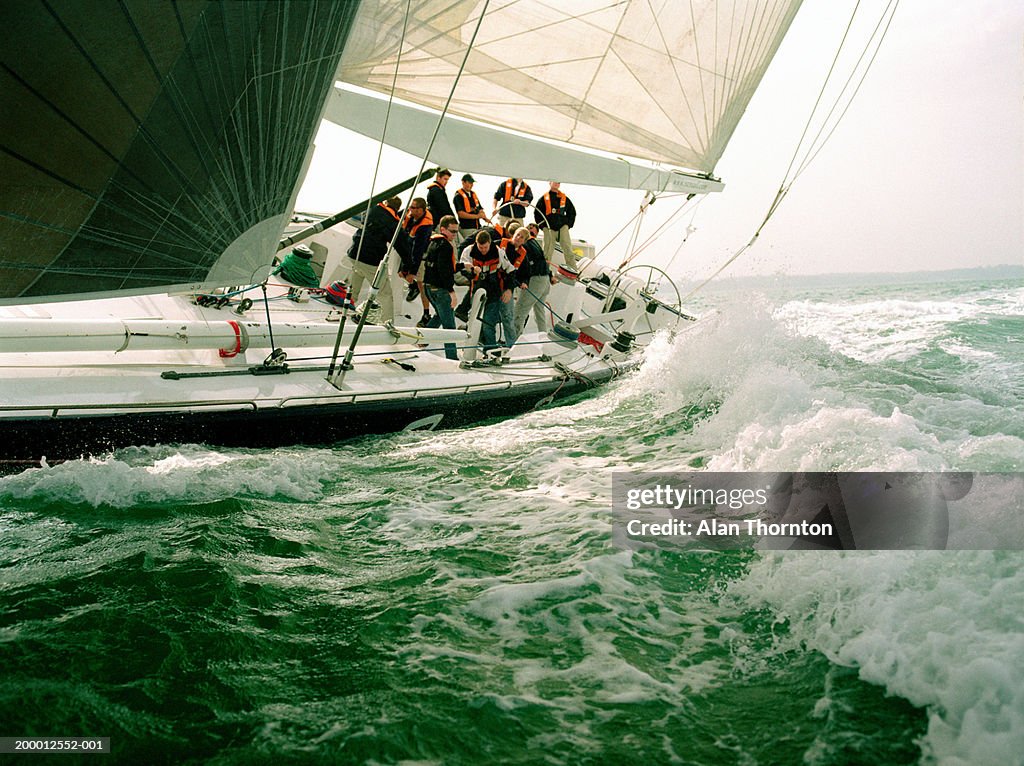 Crew sailing yacht through rough sea