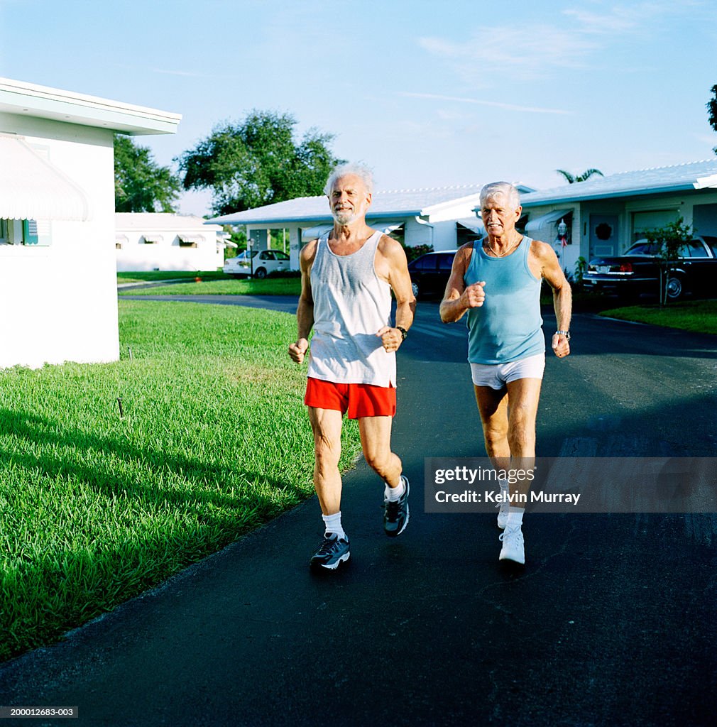 Two elderly men jogging through residential street