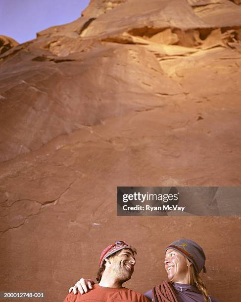 couple standing against rock face, smiling, high section, portrait - extreme hug face stockfoto's en -beelden