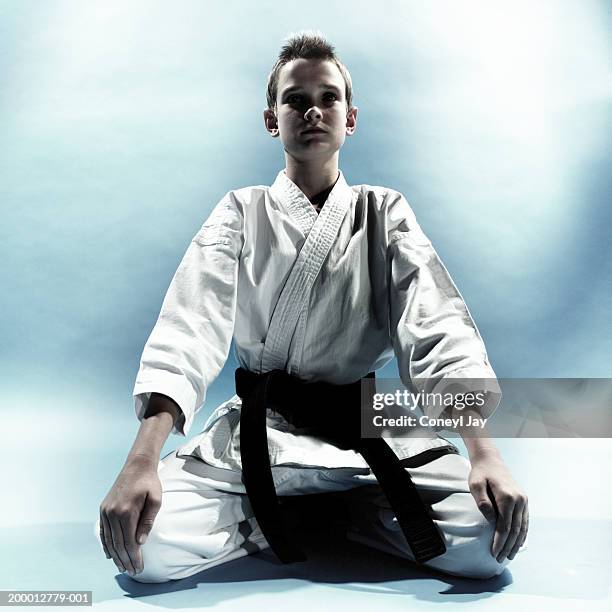 boy (11-13) wearing karate costume, kneeling - zwarte band stockfoto's en -beelden