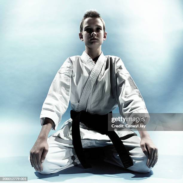 boy (11-13) wearing karate costume, kneeling - black belt stock pictures, royalty-free photos & images