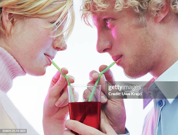 young couple sharing drink using straws, profile, close-up - pajita fotografías e imágenes de stock