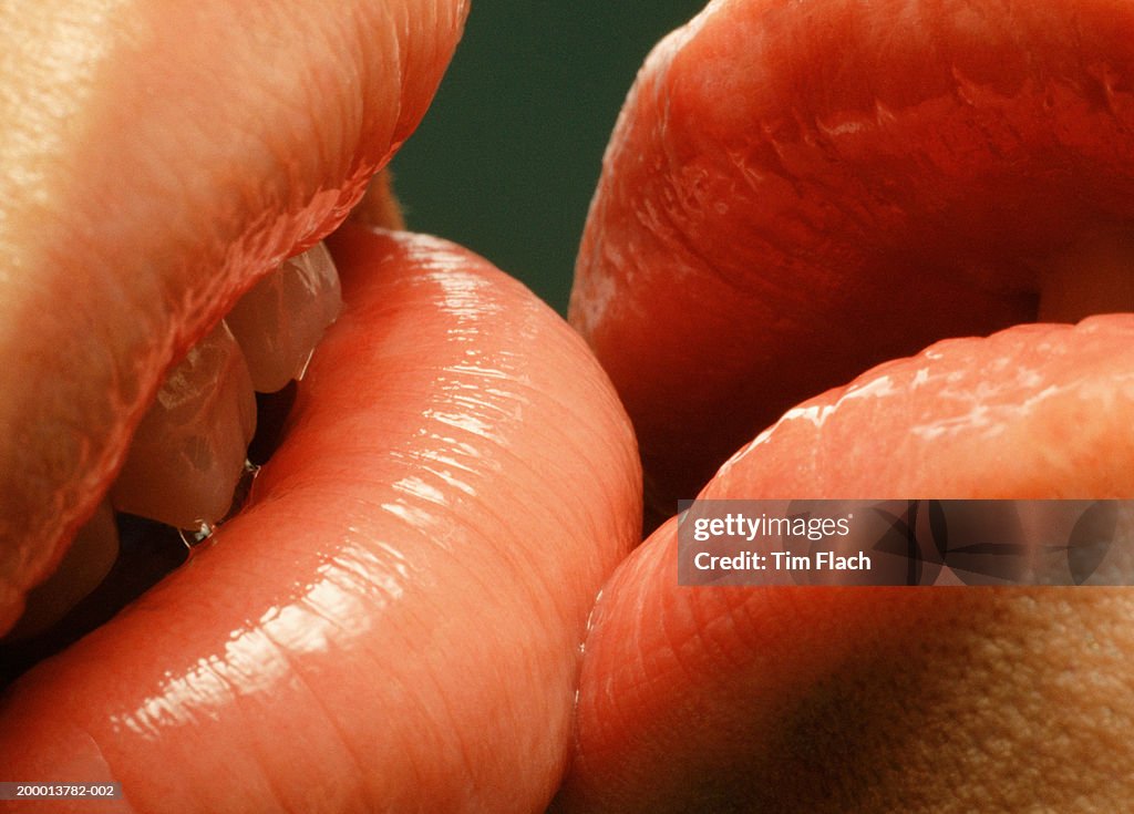 Couple with glossy lips kissing, close-up