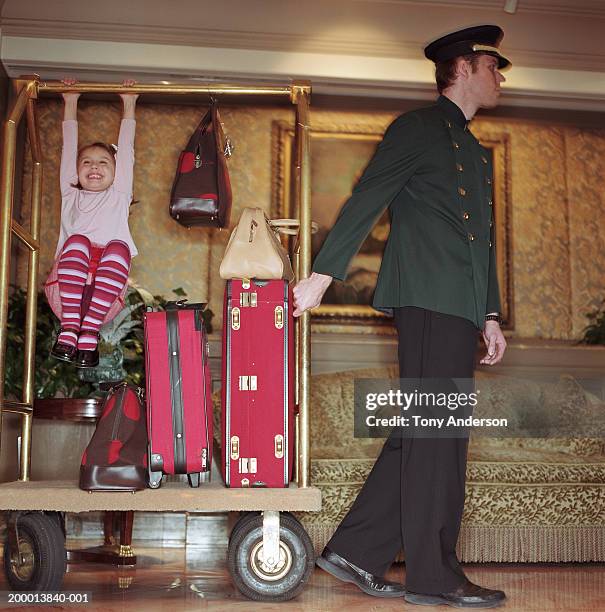 doorman pulling luggage cart in lobby, girl (4-6) playing on cart - carrito-para-equipaje fotografías e imágenes de stock