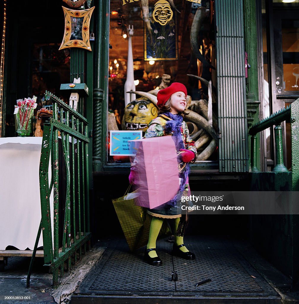 Girl (4-6) swinging shopping bags in front of shop (long exposure)