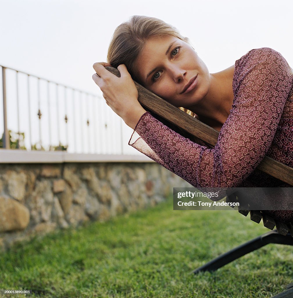 Young woman lying on lounge chair in garden, portrait, close-up