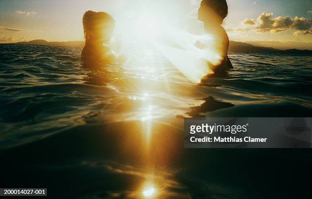 sunlight shining between two women in water - hot puerto rican women stock-fotos und bilder