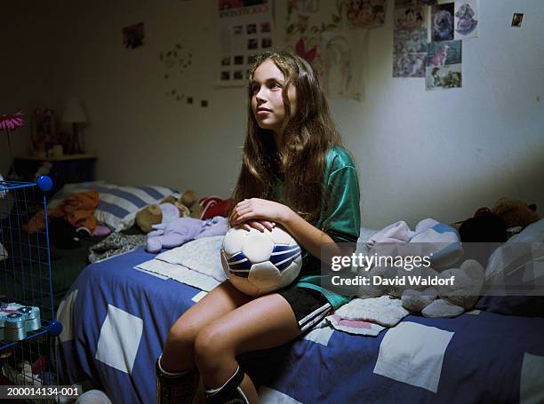 teenage girl (12-14) sitting on bed with soccer ball - fille sport photos et images de collection