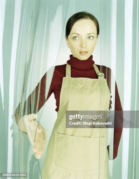 woman wearing apron, holding open plastic curtain - polyäthylen stock-fotos und bilder