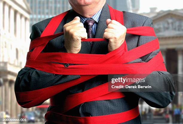 businessman bound up in red tape, mid section, close-up - bürokratie stock-fotos und bilder