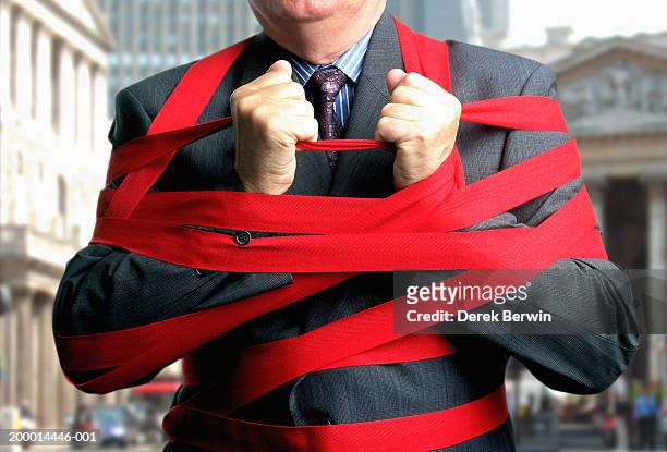 businessman bound up in red tape, mid section, close-up - bureaucracy stock pictures, royalty-free photos & images