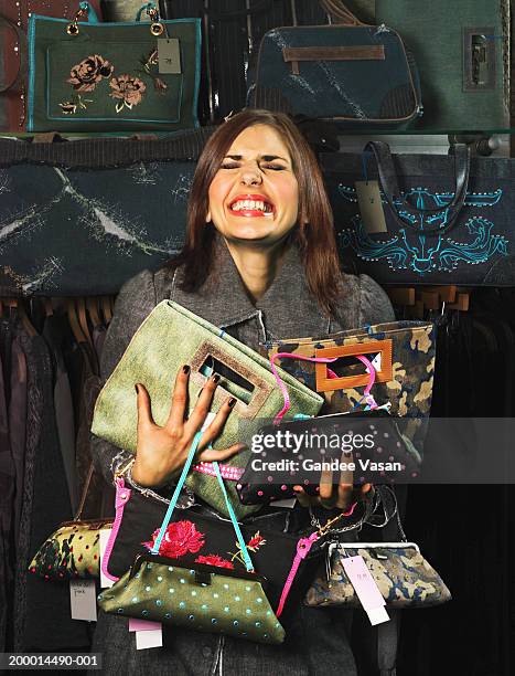 woman in shop clutching handbags, smiling - collection stockfoto's en -beelden