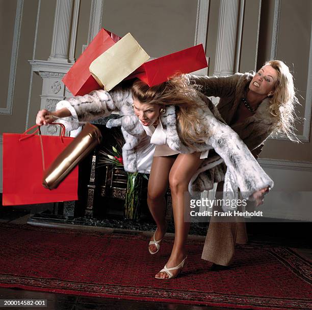 two women fighting with shopping bags, indoors - se battre photos et images de collection