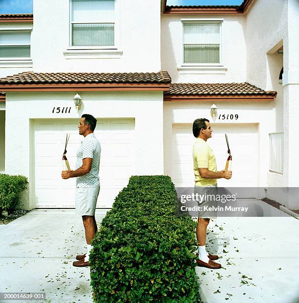 two neighbours back to back holding pruning shears - neighbour stock pictures, royalty-free photos & images