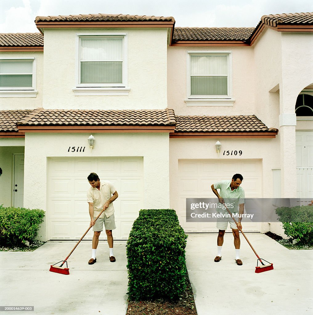 Two neighbours sweeping driveways