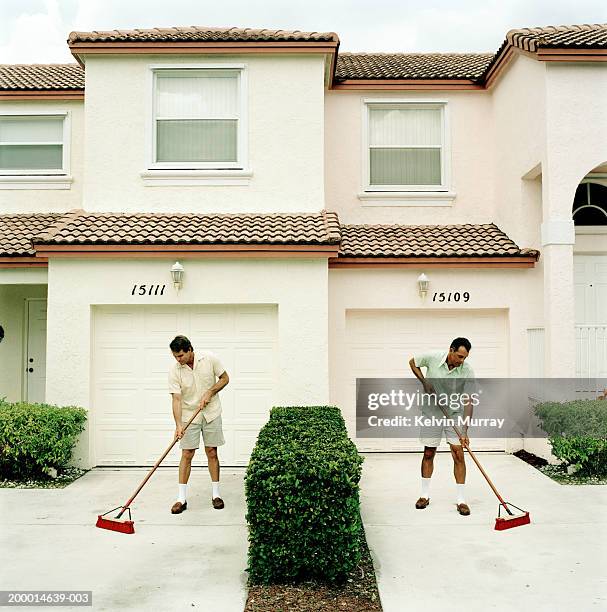 two neighbours sweeping driveways - trabalho fastidioso - fotografias e filmes do acervo