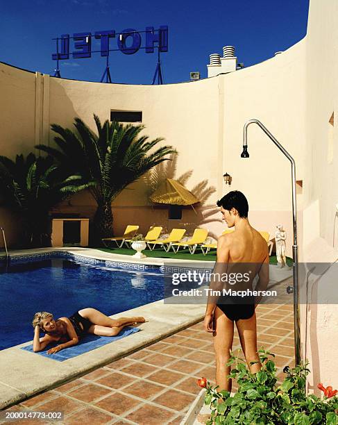 young man and mature woman looking at each other beside hotel pool - young men in speedos stock pictures, royalty-free photos & images