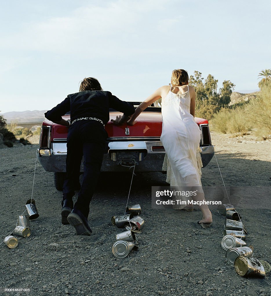 Bride and groom pushing car