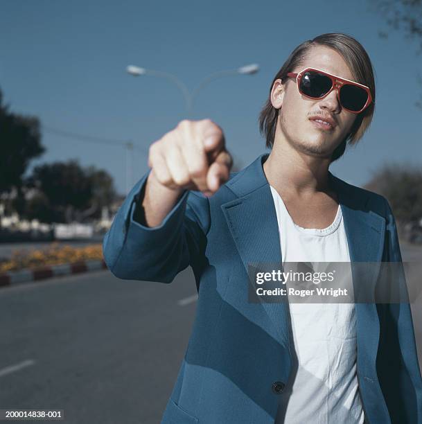 young man in street wearing sunglasses, pointing, close-up - arrogant stock-fotos und bilder