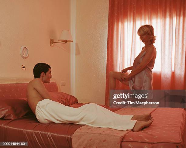 young man lying on bed, watching mature woman undress - chemise de nuit photos et images de collection