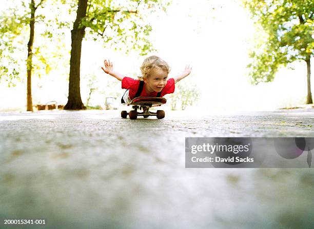 boy (2-4) coasting on skateboard, ground view - free skate - fotografias e filmes do acervo