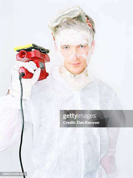 young man holding sander, face covered in white dust, portrait - white jumpsuit stock pictures, royalty-free photos & images