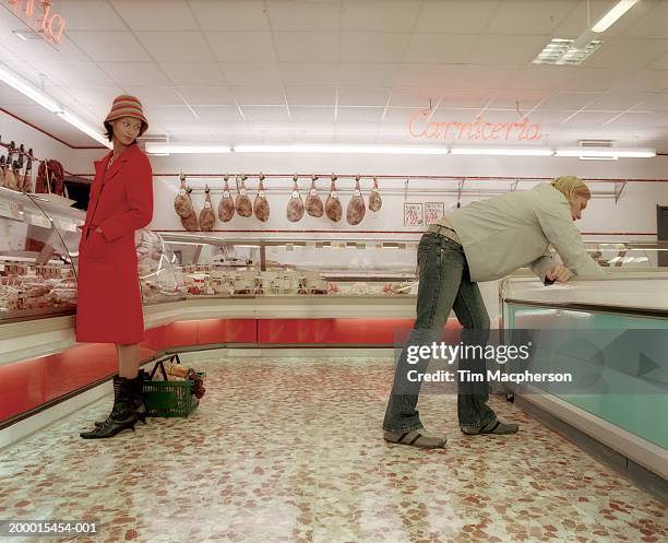 young woman looking towards man in meat section of supermarket - flirt stock pictures, royalty-free photos & images