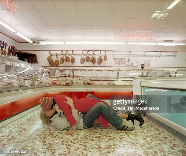 young couple embracing on floor in meat section of  supermarket - deli counter stock pictures, royalty-free photos & images