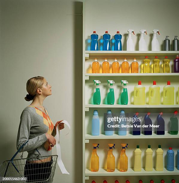 woman with shopping list and basket looking at shelf display - detersivi foto e immagini stock