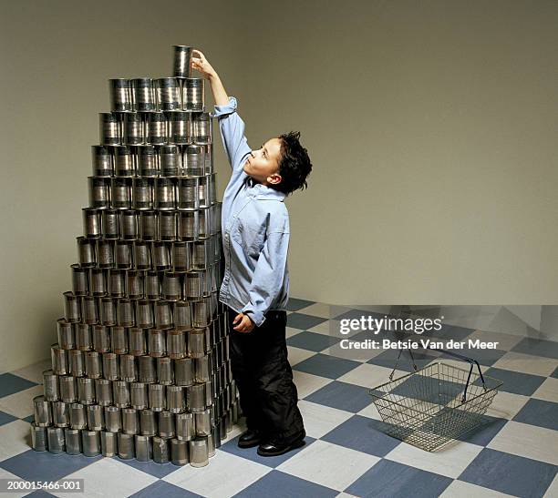 boy (6-8) taking tin can from top of stack - stacked canned food stock pictures, royalty-free photos & images