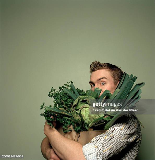 young man holding bag full of vegetables, portrait - shopping coloured background stock pictures, royalty-free photos & images