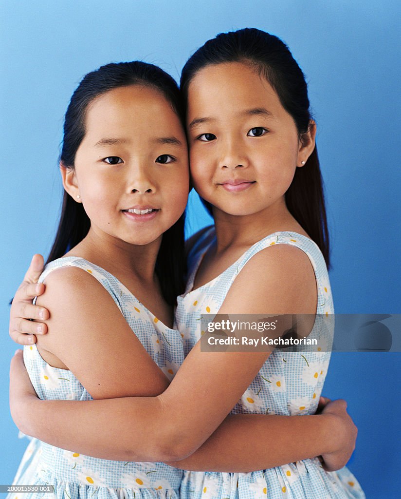 Twin girls (5-7) wearing dresses with daisy print