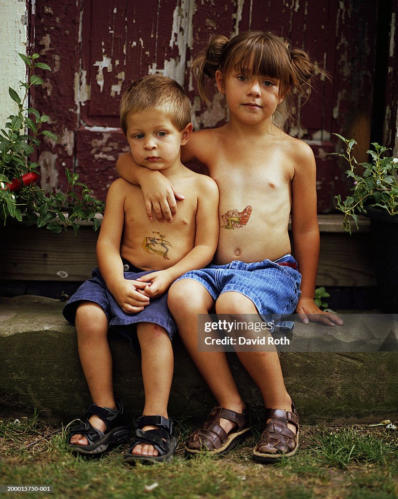 Boy and girl (3-7) with fake tattoos on stomach's, portrait