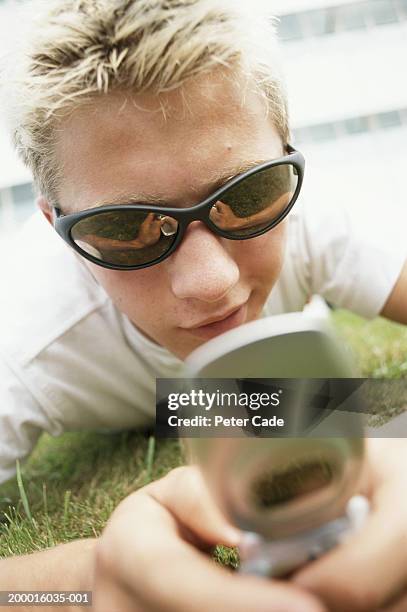 teenage boy (15-17) lying on grass using mobile phone, close-up - telefone-de-dobrar imagens e fotografias de stock