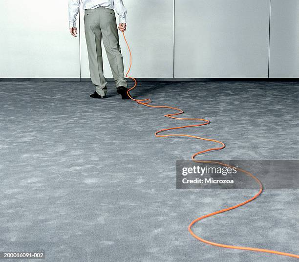 male executive dragging extension cable across office, low section - microzoa stock pictures, royalty-free photos & images