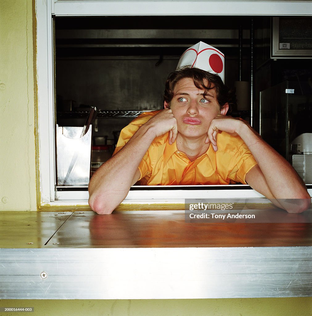 Teenage boy (16-18) behind counter at hot dog stand