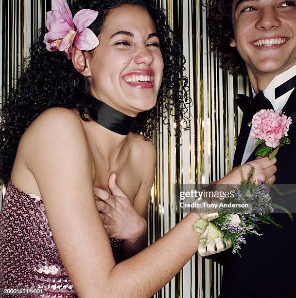 teenage girl (16-18) pinning boutonniere on date, laughing, close up - pin up girl stockfoto's en -beelden