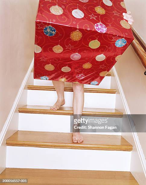 young woman carrying large wrapped box down stairs, low section - bigger photos et images de collection